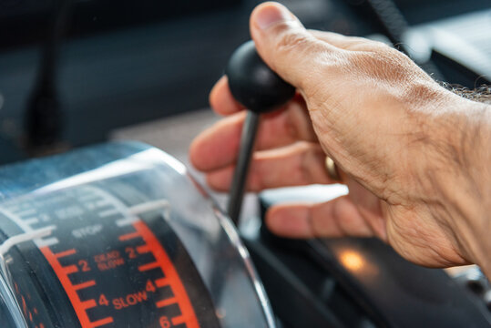 The hand of an operator grips the engine telegraph lever on the bridge of a merchant ship, ready to issue commands to control the main engine's speed, embodying precision and responsibility at sea.