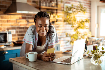 Young woman using a smart phone in the kitchen at home