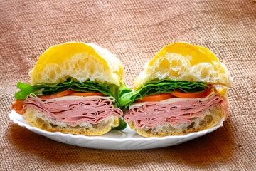Italian mortadella bologna sandwich with arugula, tomato and cheese on ciabatta bread