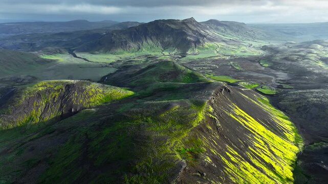 Black volcanic mountains covered by moss in the Icelandic highlands, unusual nature landscape, spectacular bird's eye view, epic shot from a drone 