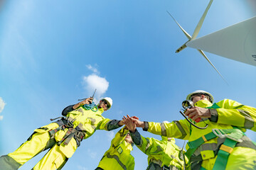 A team of engineers celebrates success after completing wind turbine maintenance at a wind farm....