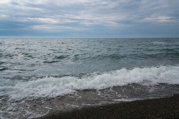 An incoming wave on the Black Sea and a pebble beach on the Sochi coast on a summer day with...