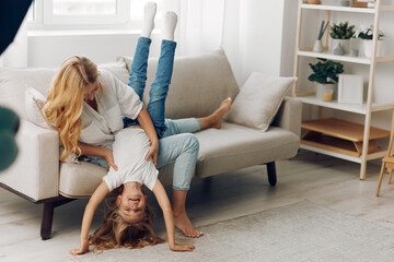 Mother and daughter sharing joyful moments on a cozy living room couch, filled with laughter and...