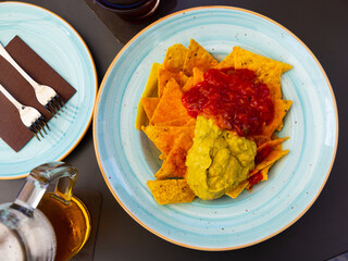 Traditional snack of Mexican cuisine is Nachos with guacamole sauce