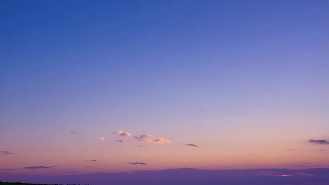 A serene pastel-colored sunset sky with soft pink and purple hues, featuring scattered clouds on the horizon.