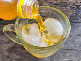 Pourinkg orange soft drink and ice cubes