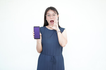 Fototapeta premium Beautiful Asian woman holds a smartphone with a blank screen, shouting with one hand over her mouth