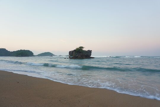 Beautiful natural scenery front of the island on the sea under bright blue sky in summer at Kondang Merak Banyu Meneng Malang Tropical Beach, East Java.