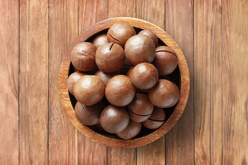 shelled macadamia nuts in bowl on wooden table background, top view. organic vegetarian food.