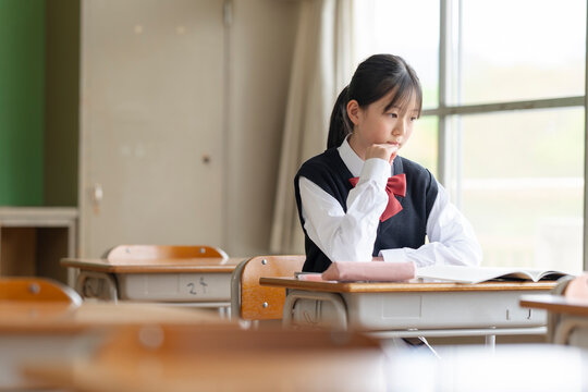学校の教室で思い悩む女子中学生