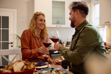 Happy couple toasting with wine during Thanksgiving dinner.