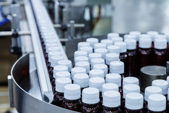 Glass bottle with cap on production line of conveyor belt at filling machine in medical factory. pharmaceutical and supplement manufacturing.