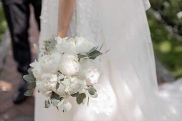 the bride in a white dress holds a wedding bouquet of flowers