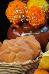 Pan de muerto, con flores de cempasúchil detrás, altar de muerto 