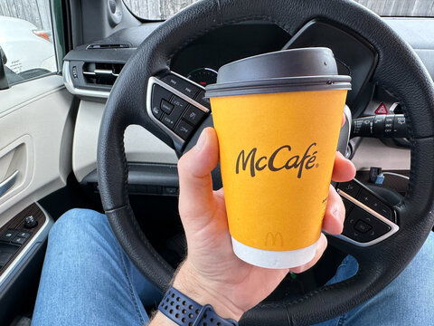Holding a cup of McCafe Mcdonald's hot coffee cup inside the car,.