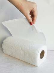 A woman's hand tears a paper towel from a roll. Roll of disposable paper towels made of virgin cellulose. Hygiene. Background, space for text. personal hygiene, hand hygiene.