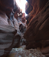 Sun shine bright between narrow rippled red rock sandstone canyon walls in Buckskin Gulch