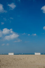 A serene and tranquil beach scene proudly showcasing quaint white huts set against a clear blue sky above