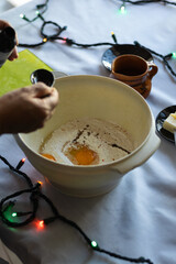 Unrecognizable person pouring vanilla extract with a ladle into a bowl with flour and eggs, for the...