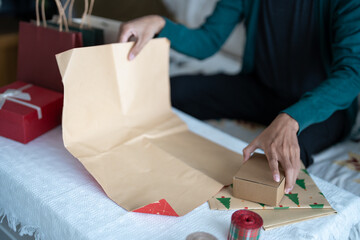 Man in sweater wrapping christmas presents with eco paper girl packing christmas gifts Xmas holiday concept