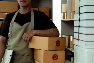 Entrepreneur of young Asian man working with laptop computer and boxes for ordering packaging from...