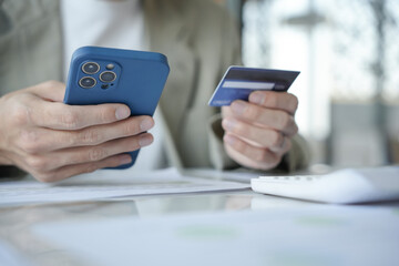 Asian Man paying with credit card on smart phone at office. Male Using Smartphone for Shopping electronic wallet Online
