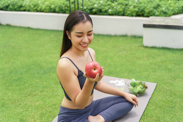 Fitness woman holding yoga mat with Fresh Apple Heathy clean vegan food before working out Beautiful&nbsp;confident asian woman practices in green park