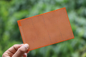 Universal double sided printed circuit board or PCB for prototyping electronics project held in the...