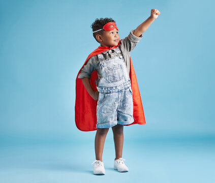 Boy, kid and superhero with mask in studio for flight, fantasy and playful with memory by blue background. Child, cape and ready with action, character and games with power for halloween party - Powered by Adobe