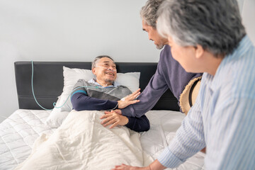 scene of old man patient lying on bed with IV drip and oxygen,smiling and talking with friends who visit him,senior couple friends giving encouragement beside