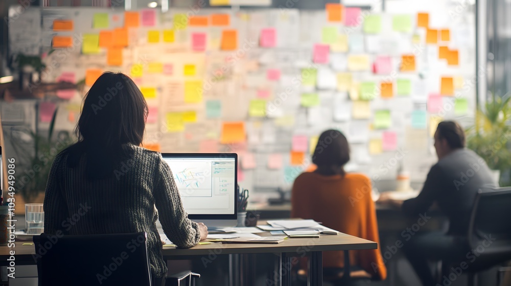 Aufkleber woman working at a desk with a computer in front of a wall covered in sticky notes.