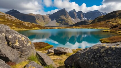 Panoramic view of a scenic lake surrounded by snow-capped mountains, reflecting the blue sky and fluffy clouds
