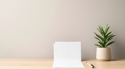 A minimalist workspace featuring a blank sheet of paper and a potted plant on a wooden desk against a neutral wall.