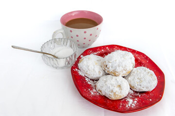 Top view of Kourabiedes, Greek butter cookies, with a cup of coffee and a crystal bowl with sugar and teaspoon, isolated in a white background.