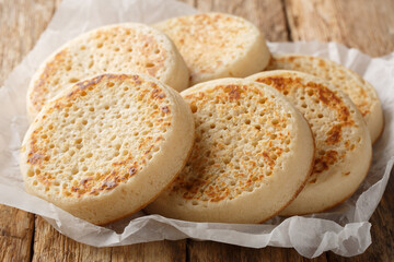 Tradition hot buttered crumpets closeup on parchment on the table. Horizontal