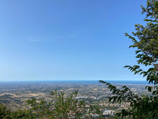 An amazing natural panorama of the San Marino suburbs surrounded by an endless blue sea strip on the horizon.