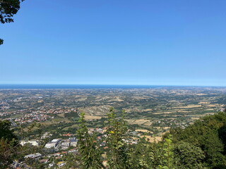 An amazing natural panorama of the San Marino suburbs surrounded by an endless blue sea strip on the horizon.