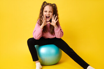 Playful kid sitting on fitness ball yelling during fun sporty screaming in playful game making paws...