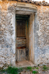 A wooden door of a village stone house in a state of decay.