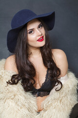 Happy fashion model woman in blue classic hat and white fur coat posing indoor, elegance fashion beauty portrait