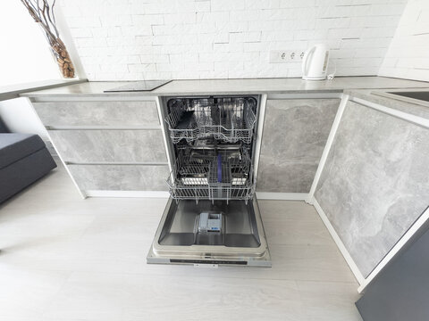 Open clean empty dishwasher in kitchen. Home appliance