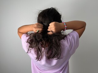 Kids holding messy hair. Wild curly black tangled hair of a little girl view from the back – Kids with Curly Hair Maintenance and Grooming Abstract Background