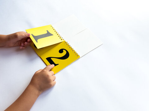 A child turns a page of learning numbers to the next number on a bright yellow background