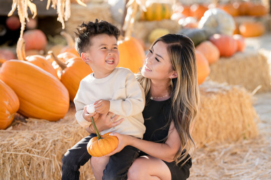 Mother and son laughing together in a pumpkin patch