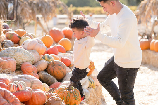 Father and son climbing through hay and pumpkins