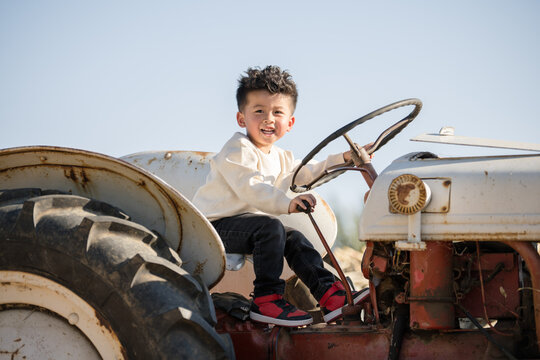 Little boy playing on an old tractor