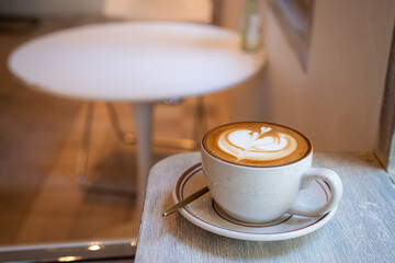 Hot coffee latte with latte art milk foam in cup mug on wood desk on top view. As breakfast In a coffee shop at the cafe,during business work concept,vintage style