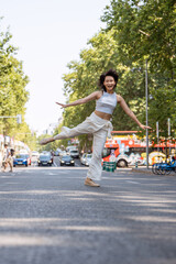 Obraz premium Carefree young woman is happily dancing in the middle of a city street, expressing her freedom and joy