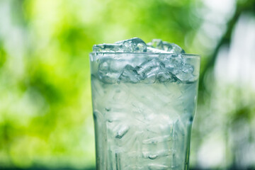 Glass of water with ice against nature background