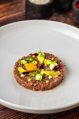 Meat tartare with quail eggs on a white porcelain plate